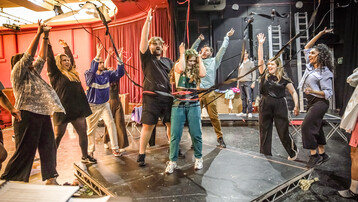 The Snowmaiden ensemble throws ribbons in the air around a woman wearing a flower crown.