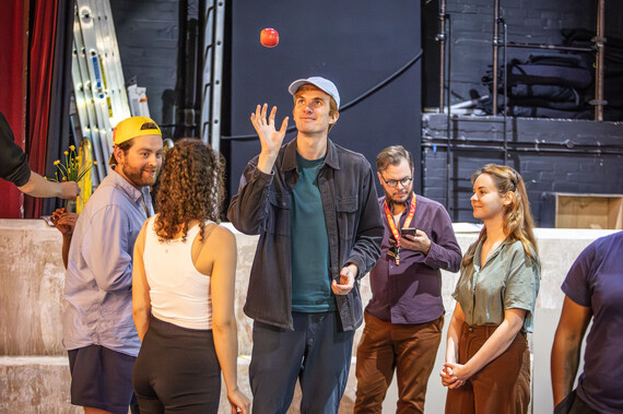 A man throws an apple in the air in the rehearsal room