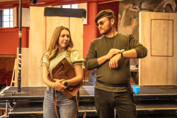 A man and woman look frustratingly at each other in the rehearsal room