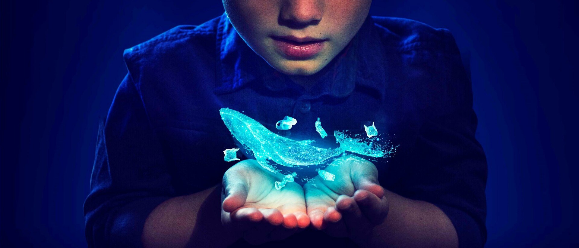 A boy has a magical whale floating in his hands. The whale is a pale see through colour and the light from the whale is lighting up the boy's face.  up.