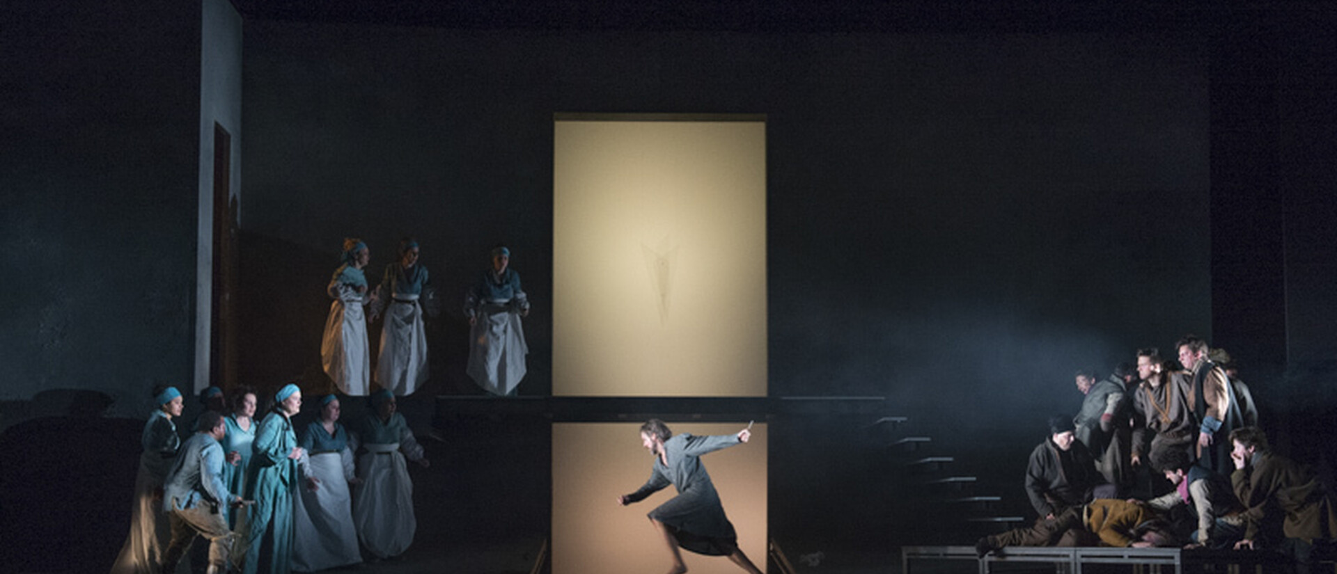 Oreste in central stage, pointing down into a hole. He is surrounded by an onlooking chorus